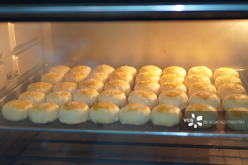 月饼、中式酥皮糕点、咸蛋黄豆饼、泰式绿豆糕和黑芝麻鸡蛋蛋糕，置于不锈钢烤架上图片素材