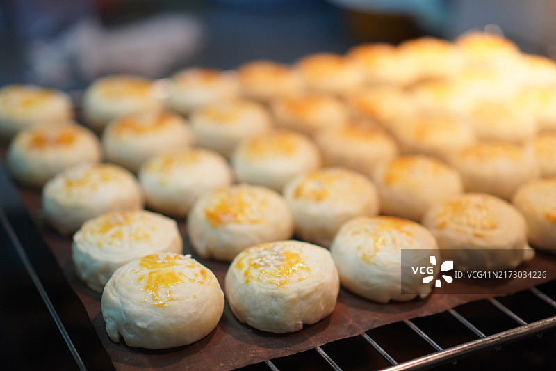 月饼、中式酥皮糕点、咸蛋黄豆饼、泰式绿豆糕和黑芝麻鸡蛋蛋糕，置于不锈钢烤架上图片素材