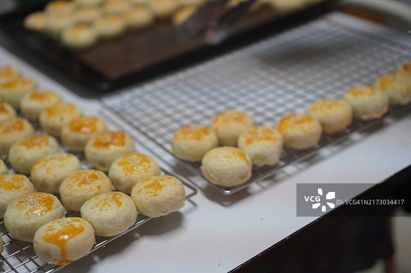 月饼、中式酥皮糕点、咸蛋黄豆饼、泰式绿豆糕和黑芝麻鸡蛋蛋糕，置于不锈钢烤架上图片素材
