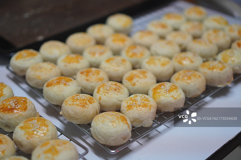 月饼、中式酥皮糕点、咸蛋黄豆饼、泰式绿豆糕和黑芝麻鸡蛋蛋糕，置于不锈钢烤架上图片素材