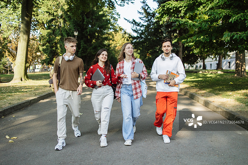 一群快乐的学生在大学课后穿过公园图片素材