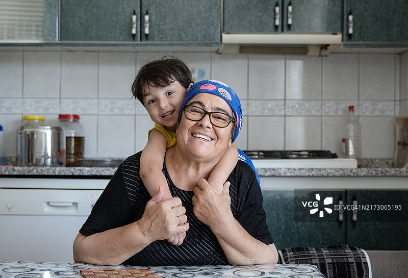 可爱的小男孩在厨房拥抱奶奶图片素材