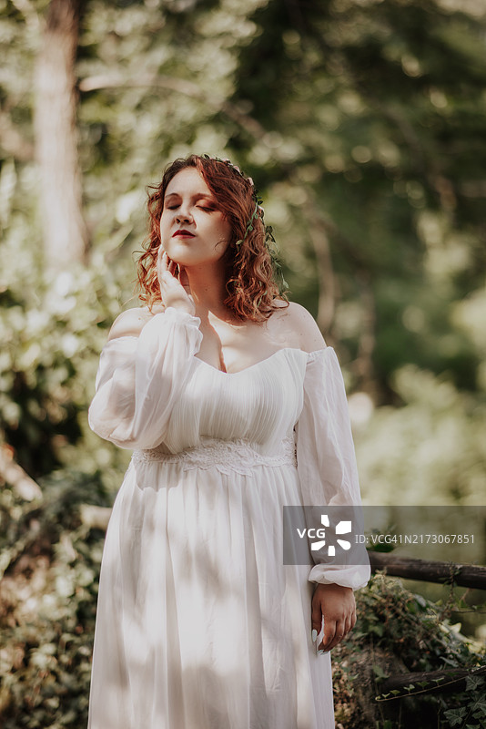 闭着眼睛享受夏日温暖的年轻红发女子图片素材