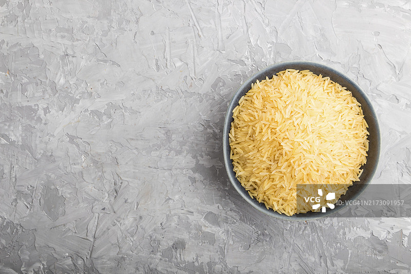 灰色背景上的蓝色陶瓷碗与金色稻米图片素材