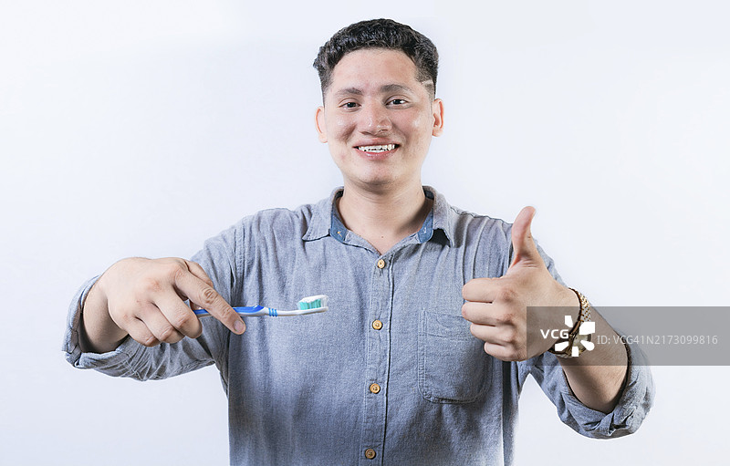 微笑的年轻男人拿着牙刷做OK手势图片素材