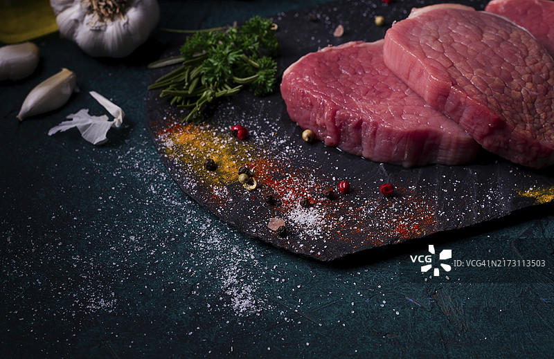 黑色石板上配香料的新鲜生牛肉小块，特写横图图片素材