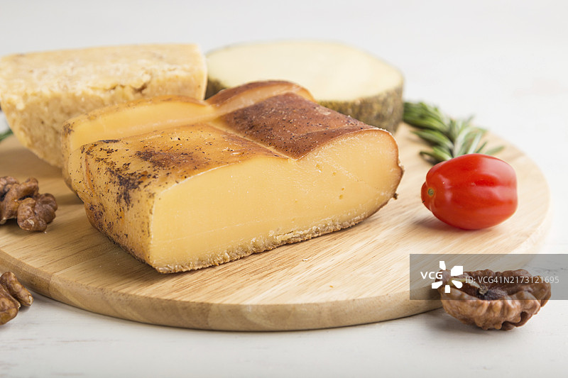 木板上的烟熏奶酪及各类奶酪，配以迷迭香和番茄图片素材