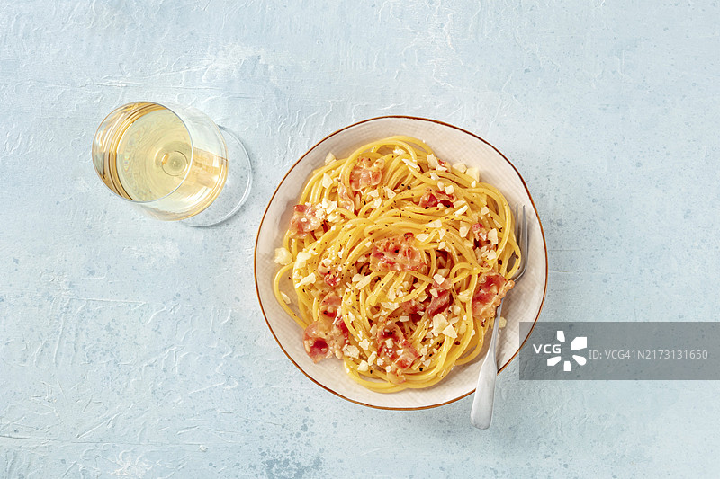 卡邦尼拉意面：传统意大利培根奶酪意面，含葡萄酒和叉子的俯视摆拍，美食摄影图片素材