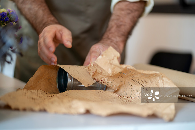 一位年长的男性小企业主正在他的家居装饰店里准备包裹图片素材