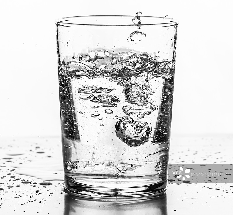 水倒入玻璃杯中，白色背景图片素材