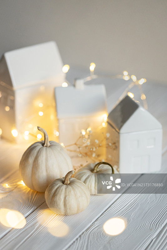 秋季装饰：白色南瓜、陶瓷小屋和花环图片素材