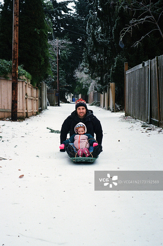父女在城市小巷一起玩雪橇图片素材