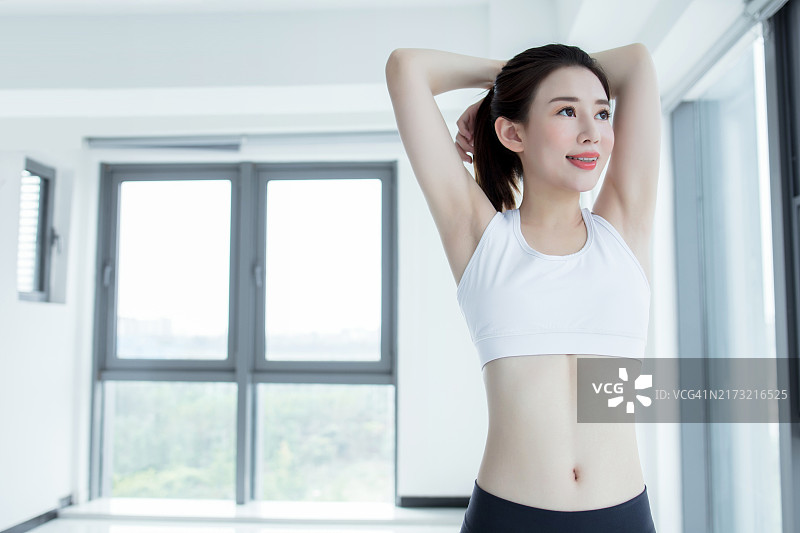 身穿黑色运动服、运动文胸和莱卡裤的运动女性，双手叉腰的正面照图片素材