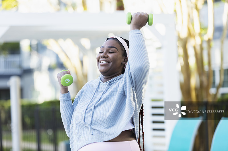 举着哑铃锻炼的怀孕非裔美国妇女图片素材