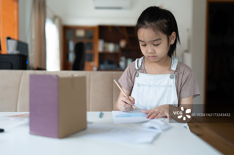 亚洲小女孩在客厅里通过绘画制作手工图片素材