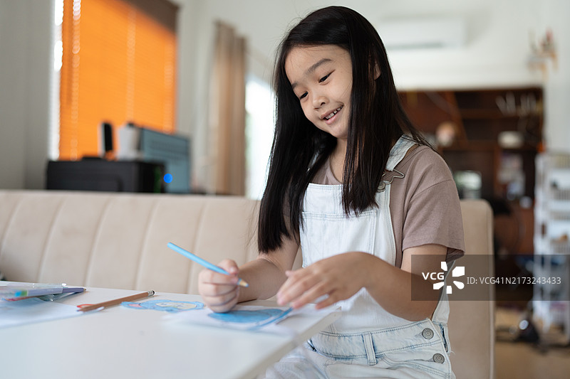 在客厅绘画制作手工的微笑亚洲小女孩图片素材