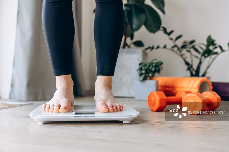 站在体重秤上的年轻女子特写：节食、健康生活方式和达成体重目标图片素材