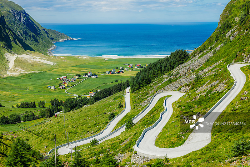 壮丽的发夹弯道路通向海边村庄和夏季山脉的北欧风光图片素材