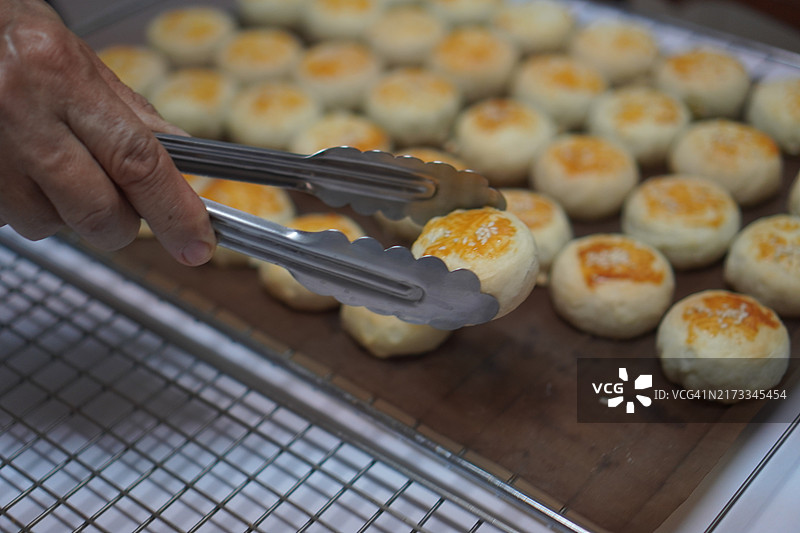 月饼、中式酥皮糕点、咸蛋黄豆饼、泰式绿豆糕和黑芝麻鸡蛋蛋糕，置于不锈钢烤架上图片素材