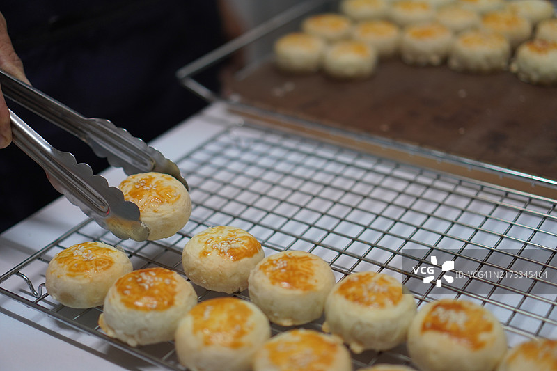 月饼、中式酥皮糕点、咸蛋黄豆饼、泰式绿豆糕和黑芝麻鸡蛋蛋糕，置于不锈钢烤架上图片素材