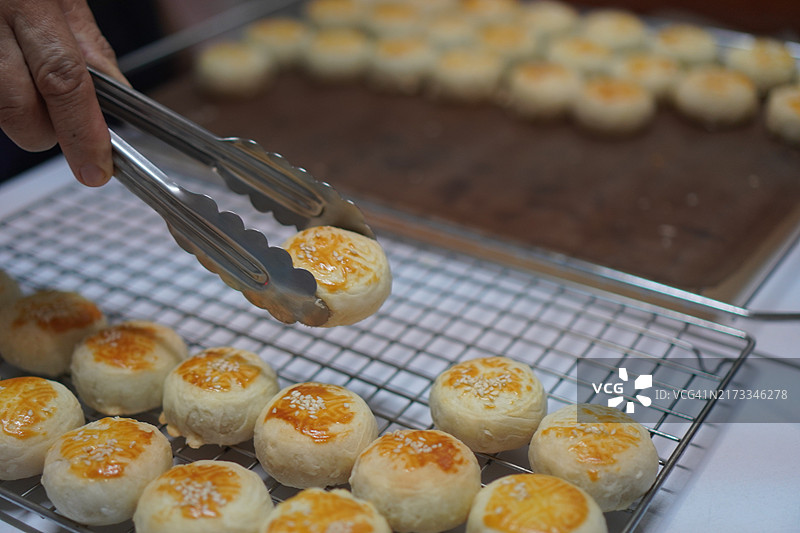 月饼、中式酥皮糕点、咸蛋黄豆饼、泰式绿豆糕和黑芝麻鸡蛋蛋糕，置于不锈钢烤架上图片素材