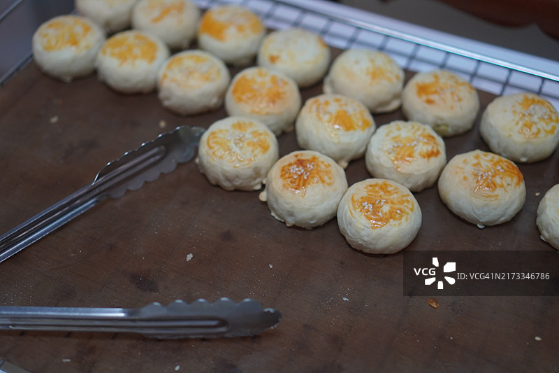 月饼、中式酥皮糕点、咸蛋黄豆饼、泰式绿豆糕和黑芝麻鸡蛋蛋糕，置于不锈钢烤架上图片素材