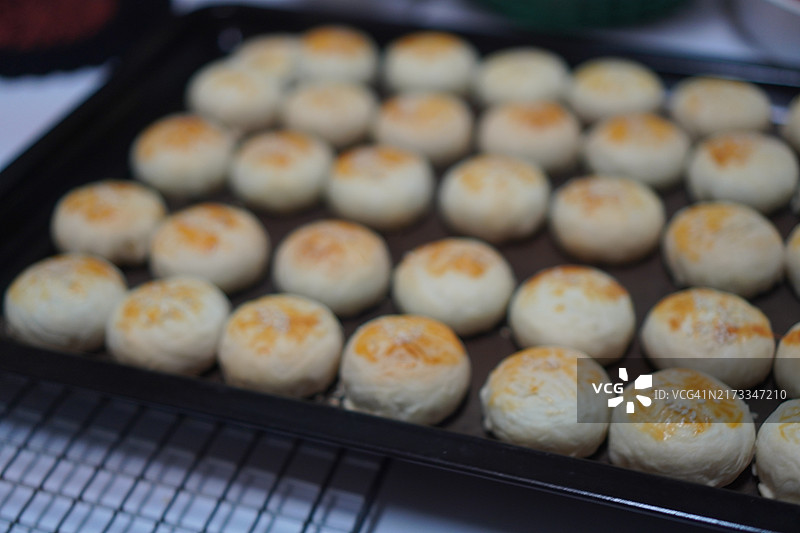 月饼、中式酥皮糕点、咸蛋黄豆饼、泰式绿豆糕和黑芝麻鸡蛋蛋糕，置于不锈钢烤架上图片素材