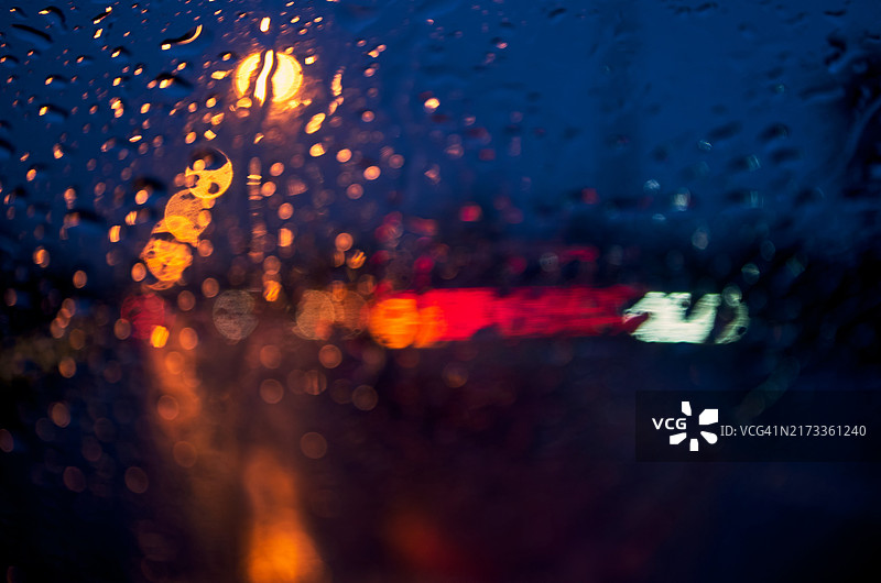 雨夜车窗上的失焦雨滴与模糊的交通灯图片素材