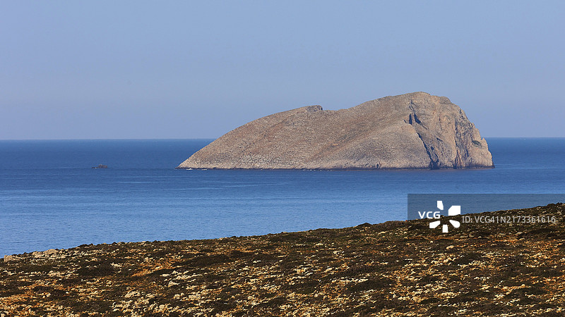 平静的蓝色大海中的大型岩石岛屿，呈现自然祥和的景象，可欣赏Pontikonisi小岛、革拉姆群岛半岛、海盗湾、巴洛斯泻湖、克里特岛西北部、希腊群岛和欧洲的景色图片素材