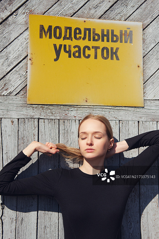 模特在带有警示牌的工厂门前摆姿势（牌子上是俄语，可翻译为模型区域）图片素材