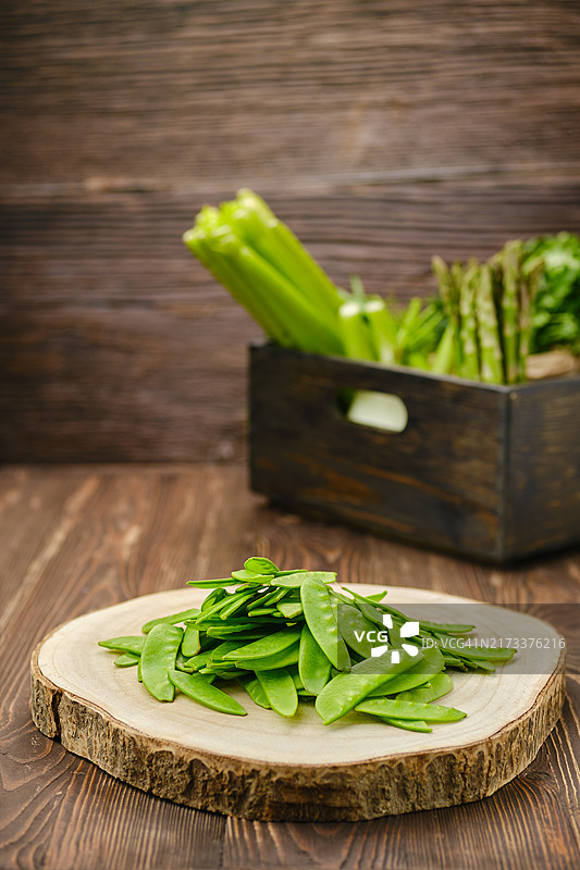 木质砧板上的新鲜豌豆荚（前景聚焦）图片素材