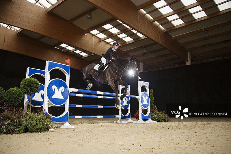 年轻女孩骑马跳过障碍图片素材