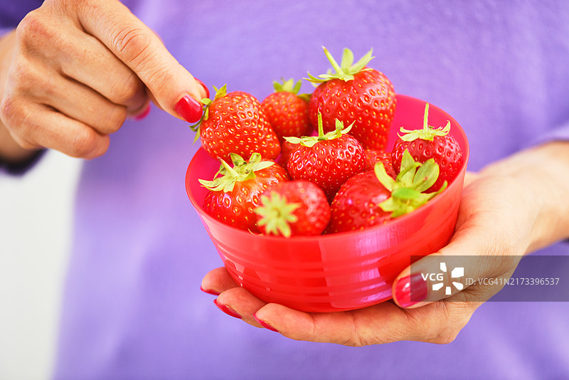 成熟的女性从碗中吃水果。图片素材