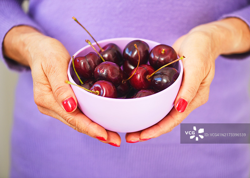 成熟的女性从碗中吃水果。图片素材