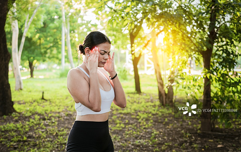 公园里患有偏头痛的女运动员：年轻跑步者头部不适图片素材