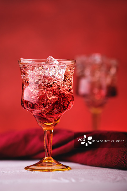 用杜松子酒和石榴苦酒调制的鸡尾酒柔焦照片，红色背景图片素材