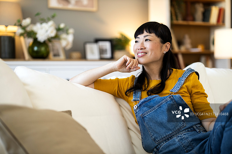 中年亚洲女性坐在房间里享受时光图片素材