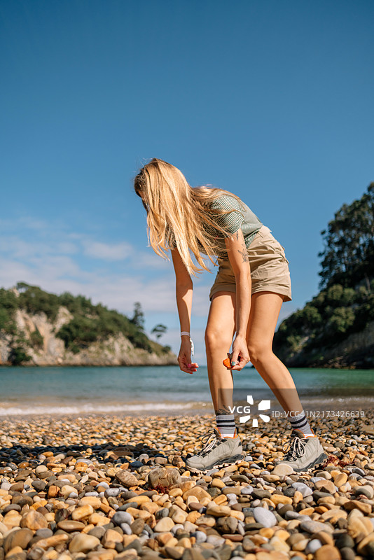 坐在海滩岩石上看天空的女子侧面图片素材
