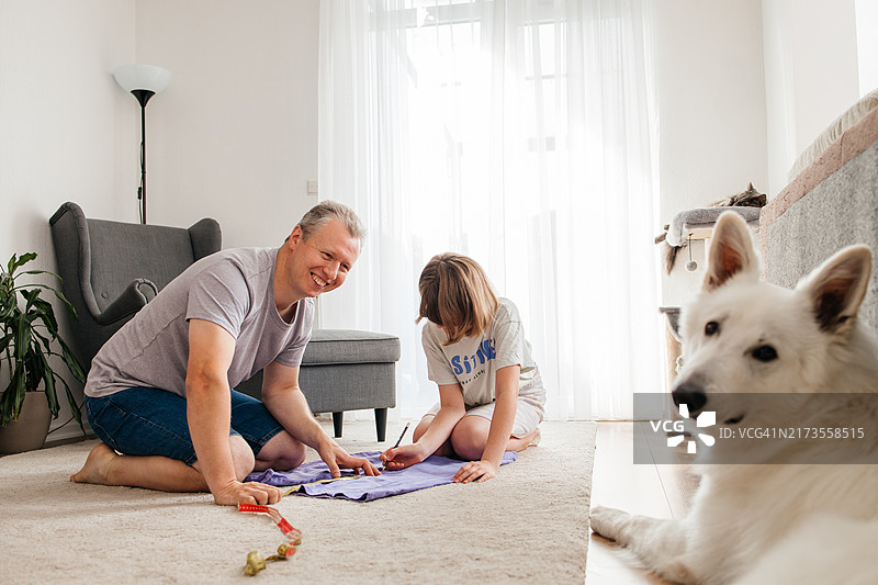 父女决定改造旧牛仔裤，赋予旧物新生命。家庭DIY项目，更新和再利用的概念图片素材