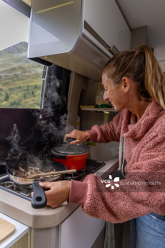 女人在露营车厨房里打开锅盖图片素材