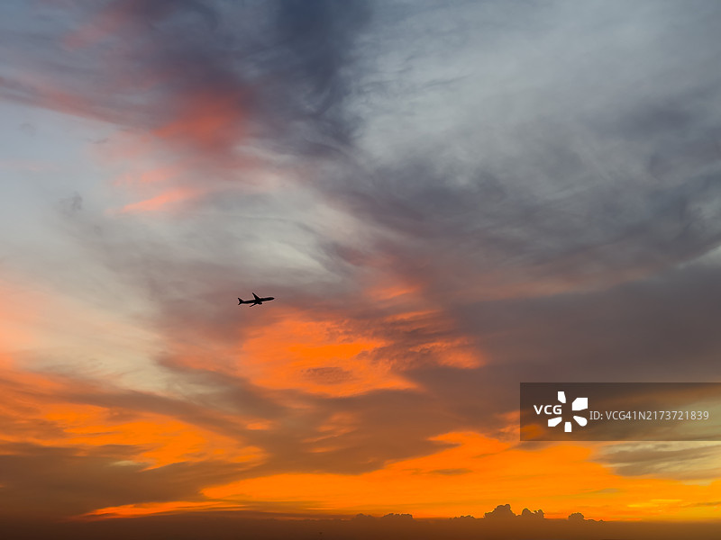 飞机在日落时分的云层中飞行图片素材
