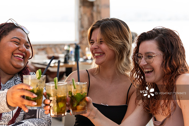 三位快乐的年轻女子举杯畅饮，一起喝鸡尾酒图片素材