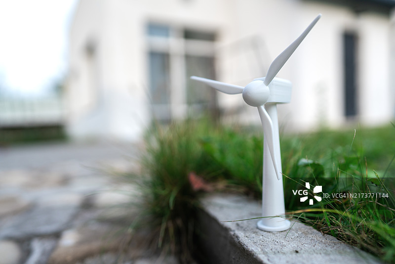 模糊房屋背景下的小型风力涡轮机模型图片素材