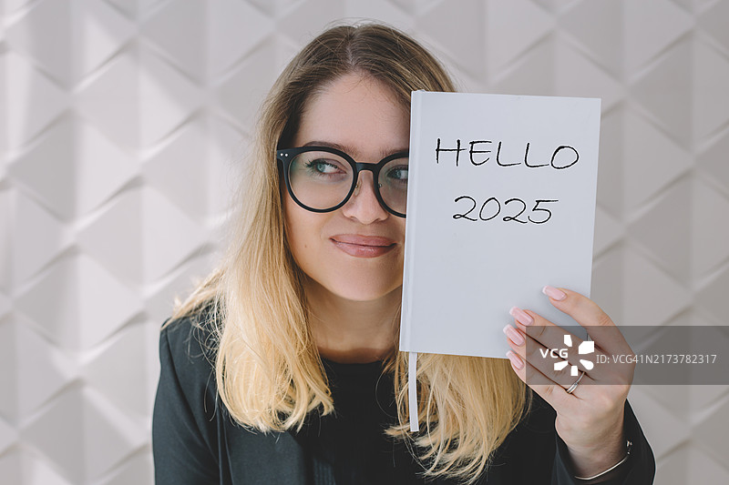 女人拿着写有2025年问候语的笔记本图片素材