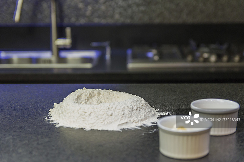 黑色花岗岩桌上的小麦粉堆，准备披萨面团图片素材