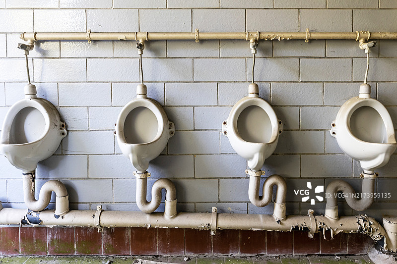 废弃建筑物洗手间里的四个小便池图片素材