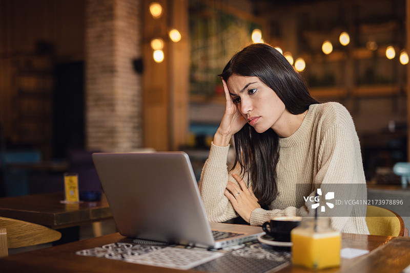 看着笔记本电脑的忧虑的女人图片素材