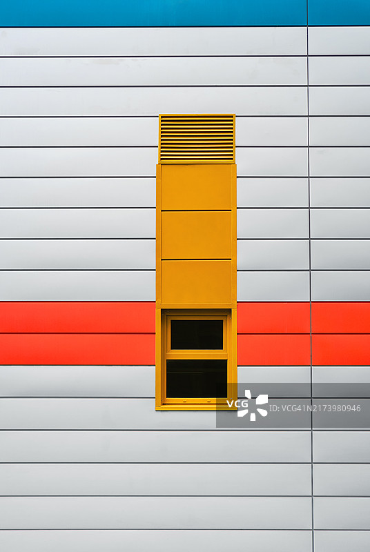 鲜艳色彩的现代建筑外墙，黄色窗户和红蓝色条纹图片素材