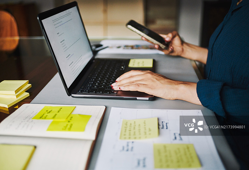 专注的女性在笔记本电脑上工作，旁边有黄色便签纸图片素材