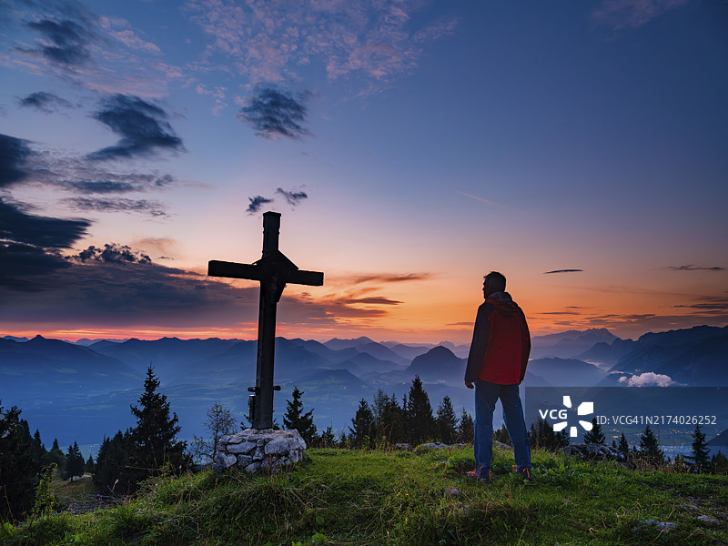 黎明时分，登山者站在阿霍恩比克森科普夫山顶十字架旁，德国巴伐利亚贝希特斯加登图片素材